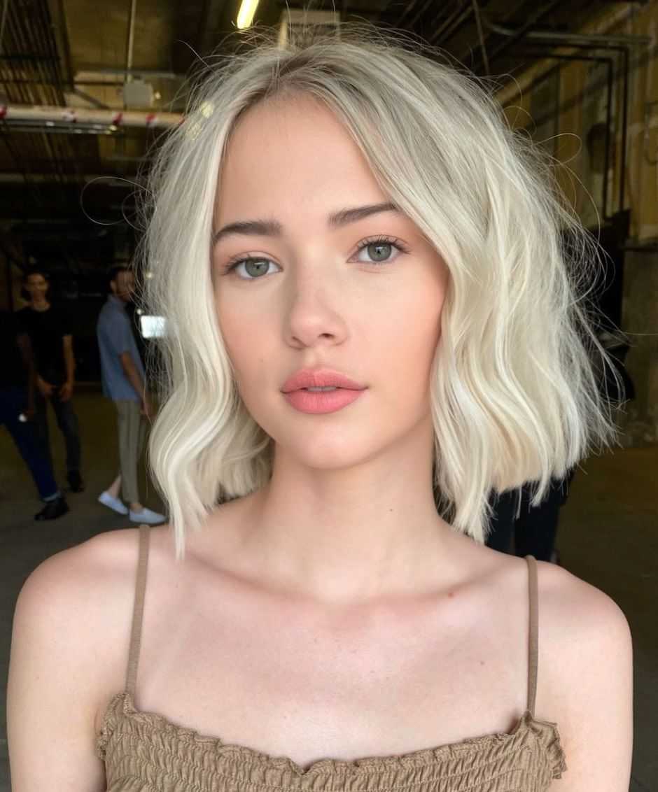 Young woman with short blonde hair in a dimly lit industrial setting.