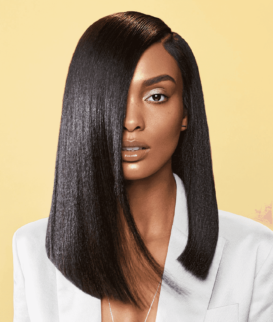 Model with sleek, straight hair and stylish outfit on a yellow background.